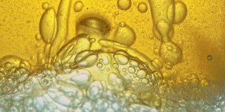 燃料，即金黄色的油，倒入实验室的玻璃容器中，释放出类似泡沫的气泡。