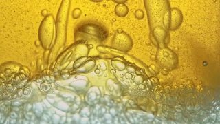 燃料，即金黄色的油，倒入实验室的玻璃容器中，释放出类似泡沫的气泡。视频素材模板下载