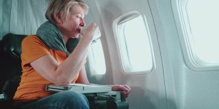 55岁的成熟女性在飞机上望向窗外。