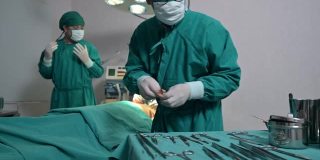 身穿手术服的外科医生团队正在选择手术设备，在手术室为受伤的病人进行手术