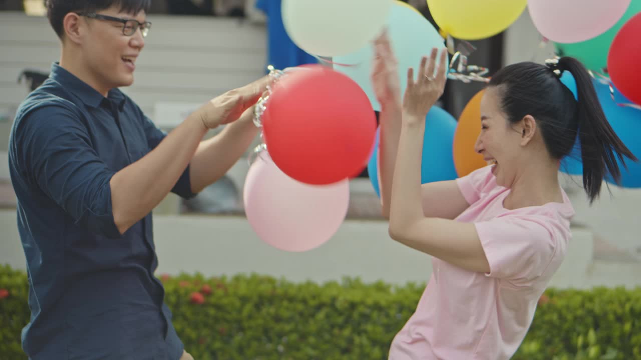 SLO MO亚洲夫妇拿着彩色气球