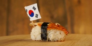 寿司上面有鱼、米饭、海藻和韩国小国旗，在木制的转盘上旋转。