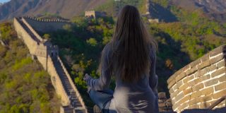 一个年轻女子坐在中国长城上沉思的慢动作镜头。塔拉维尔到中国的概念