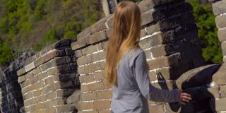 一个年轻的女人透过中国长城的开口处。这座墙在山的一侧开始倒塌