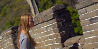 一个年轻的女人透过中国长城的开口处。这座墙在山的一侧开始倒塌
