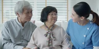 幸福的亚洲老年夫妇与在家庭护理坐在沙发微笑沙发看着相机与享受退休或隔离时间合影。亚洲老年人的生活方式。