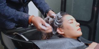 正在发廊用洗发水洗头的女士。美容师在美容院为女顾客洗头。美发美容沙龙概念。