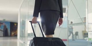 近距离观察女空乘人员拖着行李或手提箱走向机场候机楼。乘务人员职业概念。