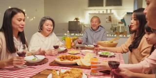 快乐的家庭时间和关系，亚洲大家庭有圣诞派对，在家里一起吃食物。爷爷很高兴看到他的孩子、侄子在餐桌上吃东西、碰杯。