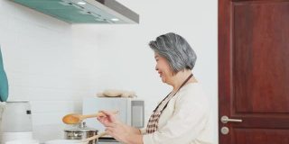 夫妇老亚洲长者幸福生活在家庭厨房。爷爷和奶奶一起煮沙拉菜，快乐地微笑着一起享受退休生活。老年人的关系和活动。