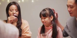 一个亚洲小女孩喜欢在圣诞节和新年聚会上和家人一起吃她的酥脆炸鸡。孩子们觉得和父母和祖父母在一起很开心。