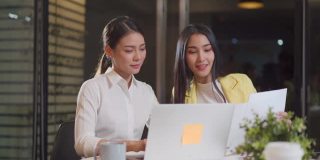 亚洲青年商务人士小组在办公室举行讨论会议。女性有头脑风暴和加班时的团队合作。公司的现代同事工作到深夜。