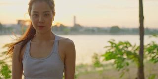 肖像快乐的亚洲年轻美丽的女人站在傍晚日落在大街上的公园。健身健硕的运动员在户外进行慢跑健身运动，以保持身体健康。