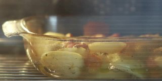 一盘肉和土豆放在烤箱里的玻璃碗里烤着