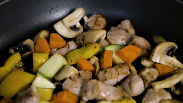 厨师用热锅烹饪鸡肉和蔬菜
