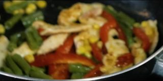 厨师用热锅烹饪鸡肉和蔬菜