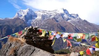 尼泊尔喜马拉雅山昆布纳姆切巴扎村的一堆石头上挂着五颜六色的佛教经幡，在风中飘扬，还有雄伟的孔德里峰。视频素材模板下载