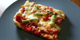 女人拿起一块自制的披萨，配上蔬菜，火腿和奶酪放在白色的盘子里。最好的意大利美食。最喜欢的食物。隔离期间做饭。