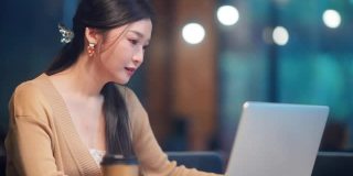 美丽的亚洲女人在休闲服装使用笔记本电脑工作电话视频会议