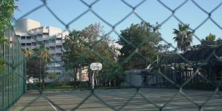 高高的金属围栏后面空荡荡的封闭篮球场。