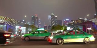 汽车在镜头前分散开来，背景是广州的摩天大楼。大城市的夜生活
