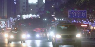 汽车在雨中行驶，车灯在画面中闪烁。大城市夜间的交通