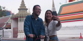 潮男美女在旅游著名景点(卧佛寺)时用手机搜索信息;曼谷泰国