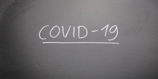 在黑板上手写“Covid-19”。