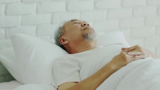 亚洲老人闭上眼睛微笑睡觉和甜蜜的梦在卧室的床上在早上感觉如此放松和舒适，保健和睡眠的概念视频素材模板下载