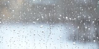 水滴飞溅到玻璃上。雨天的窗户。用大滴的水或雨浸湿玻璃杯。在大雨期间水滴在一个清晰的玻璃表面的视频。滴水