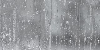 水滴飞溅到玻璃上。雨天的窗户。用大滴的水或雨浸湿玻璃杯。在大雨期间水滴在一个清晰的玻璃表面的视频。滴水