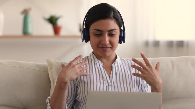 戴耳机的女人用视频会议和笔记本电脑和朋友聊天
