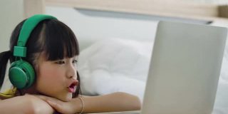 亚洲小女孩在家里学习在线课程。
