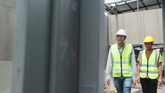 亚洲结构工程师和工人在建筑工地握手。所有人在建筑工地行走时须戴上安全帽。商业交易、并购概念