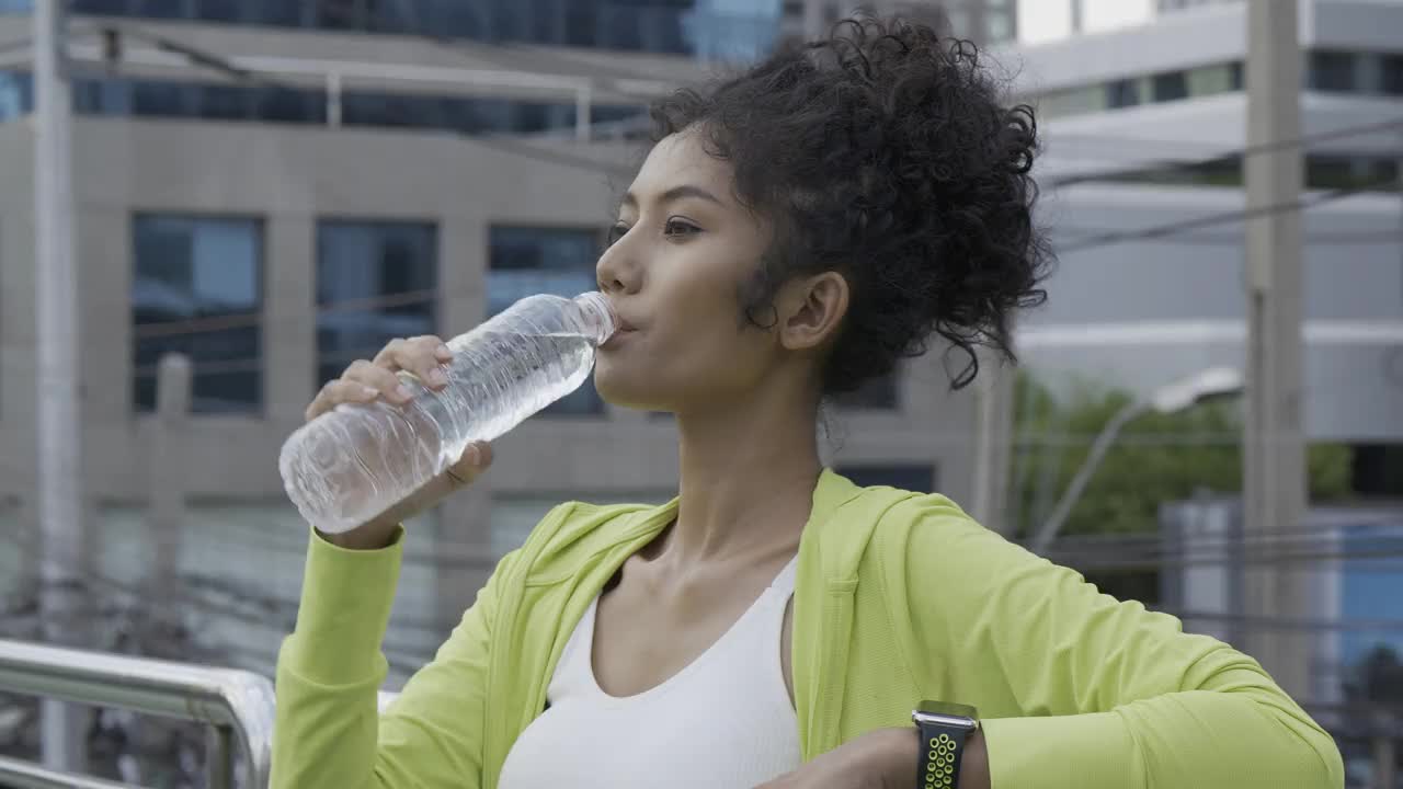 运动女孩在城里喝水。