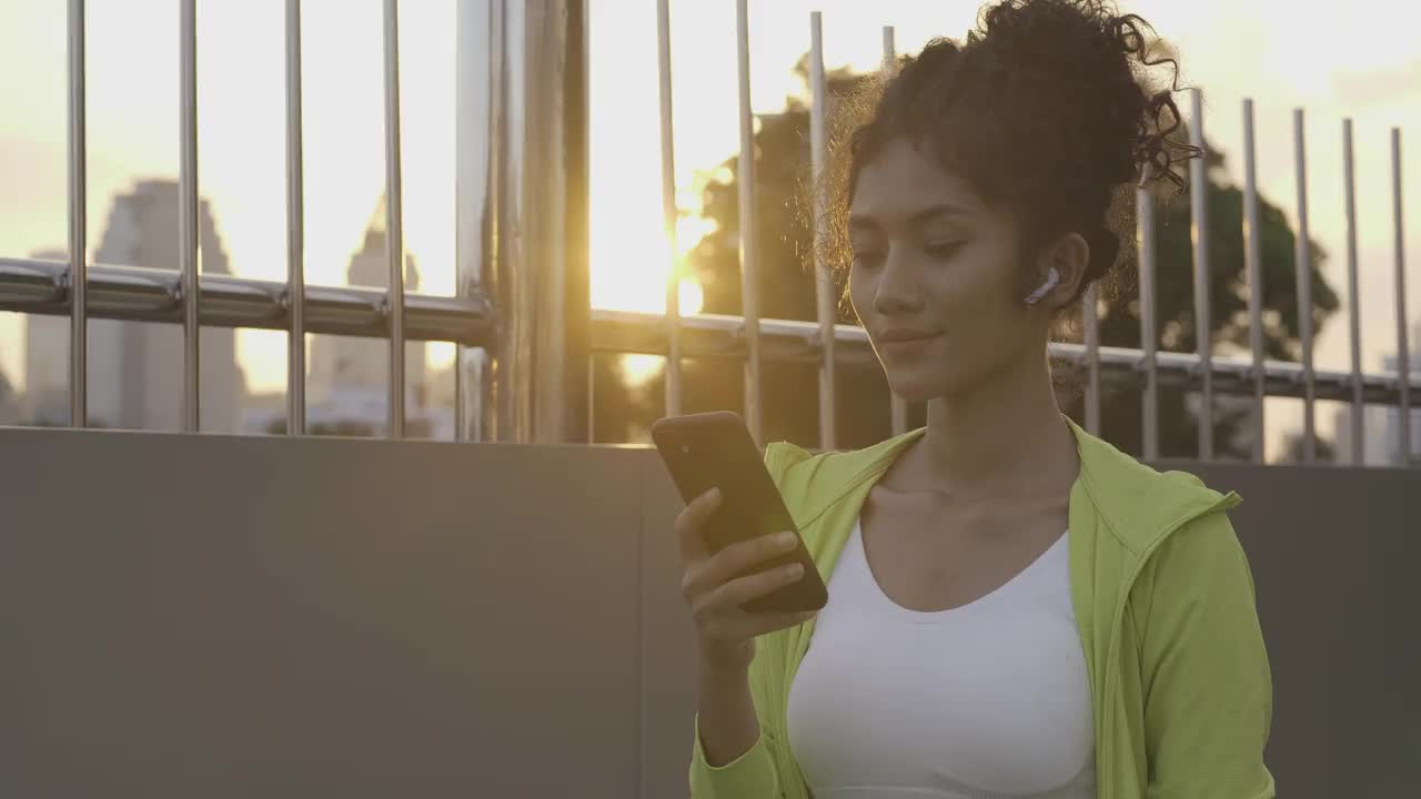 年轻女子在城市锻炼时使用智能手机。