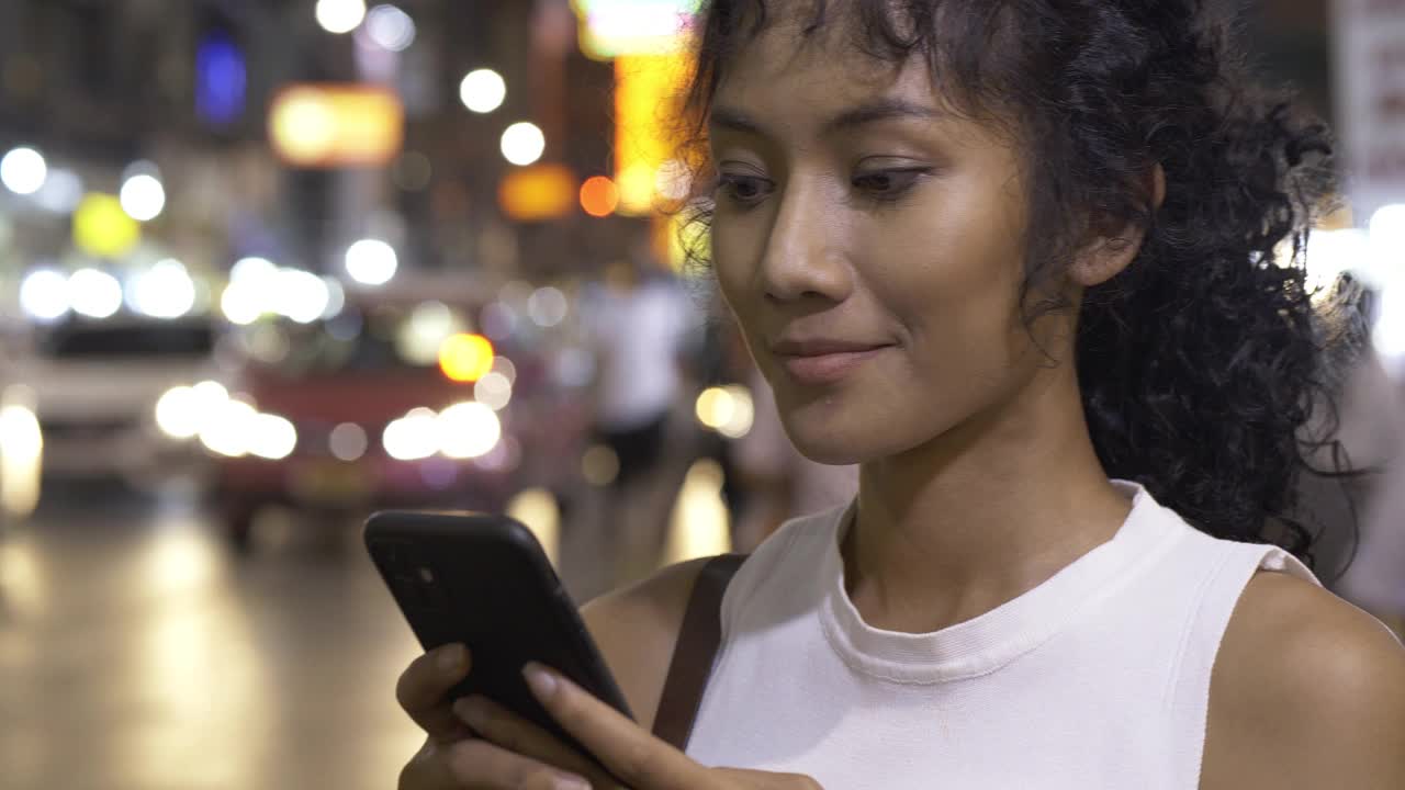 一个美女在夜市用智能手机。
