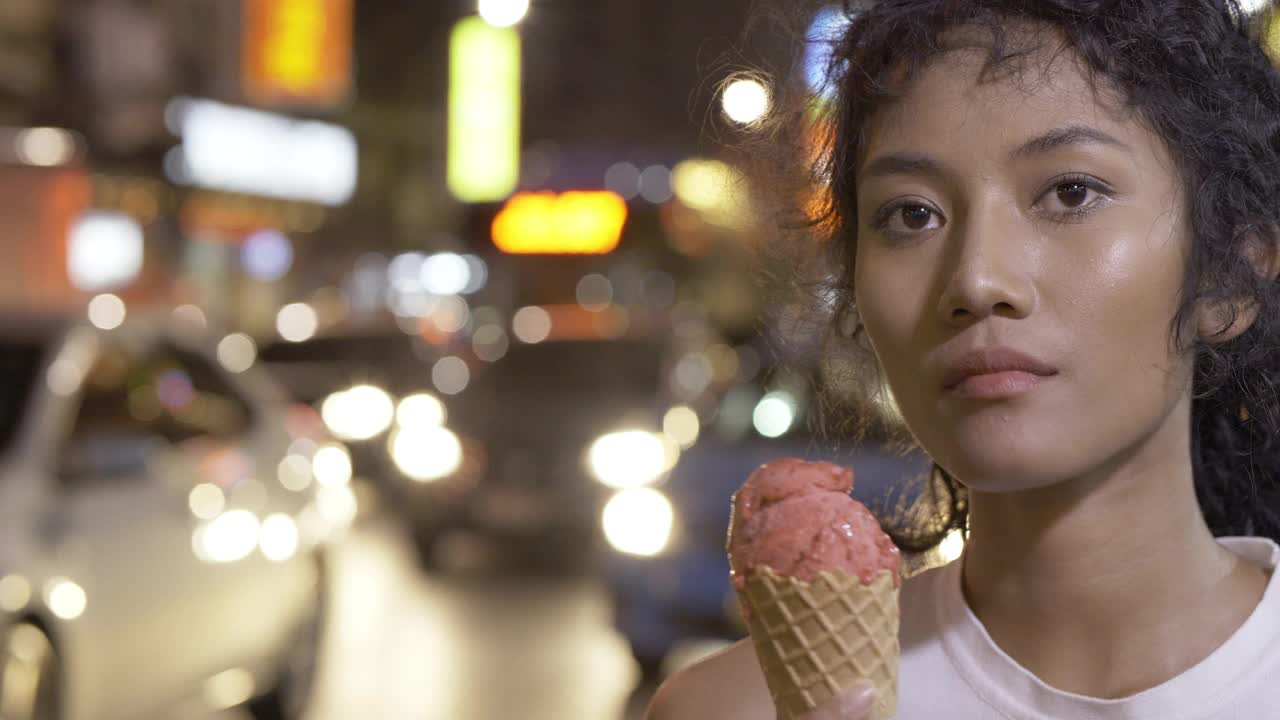 美丽的亚洲女人在夜市吃冰淇淋的肖像。