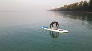 无人机航拍，早晨在SUP Board (Stand - Up Paddle Board)户外锻炼女性瑜伽伸展身体。早晨在阳光柔和的海滩上练习瑜伽。视频素材模板下载