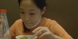 快乐的亚洲女孩与家人一起在餐厅吃面条、素喜烧、涮锅或火锅，生活方式理念。