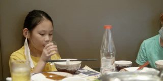快乐3亚洲女孩与家人一起在餐厅吃素喜烧、涮涮锅或火锅，生活方式理念。