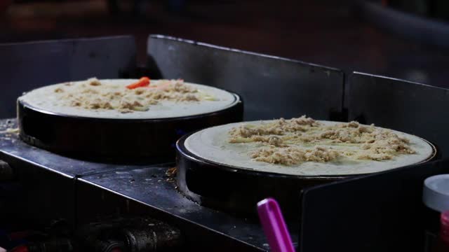 在夜市制作可丽饼甜点的特写。泰国街头小吃