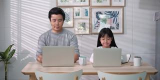 亚洲家庭的商人工作和学生女孩在家里学习。被隔离在家的爸爸和女儿在网上开会的开心表情。呆在家里。