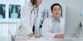 两位医生在医务室的电脑屏幕上分析讨论