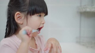 亚洲可爱的小女孩或小孩在浴室用牙刷刷牙。口腔卫生保健理念。视频素材模板下载