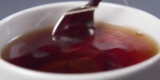 将茶匙和茶包浸在热水中，然后在一个白色的杯子里泡茶