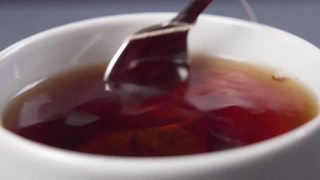 将茶匙和茶包浸在热水中，然后在一个白色的杯子里泡茶视频素材模板下载