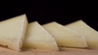 一块硬奶酪落入一堆切片羊奶酪的特写镜头。微距镜头视频素材模板下载