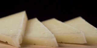 一块硬奶酪落入一堆切片羊奶酪的特写镜头。微距镜头