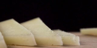 切成薄片的硬质农场奶酪在木砧板上特写